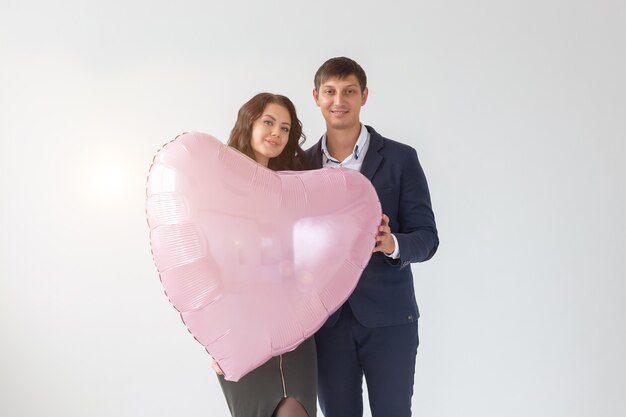 Schöne junge Frau mit Herzform-Luftballon auf weißem Hintergrund mit Kopienraum. Frau am Valentinstag. Symbol der Liebe.