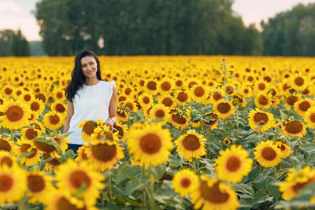 Schöne junge Frau mit Hut auf einem Sonnenblumenfeld