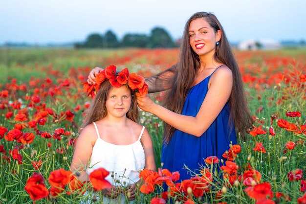 Schöne junge Frau mit Kind Mädchen im Mohnfeld glückliche Familie Spaß in der Natur Sommerzeit