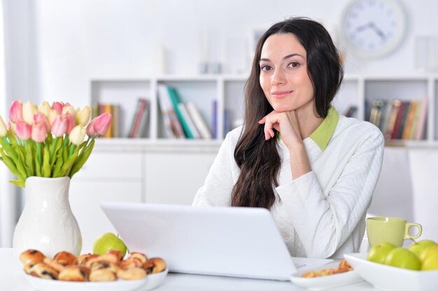 Schöne junge Frau mit Laptop am Tisch