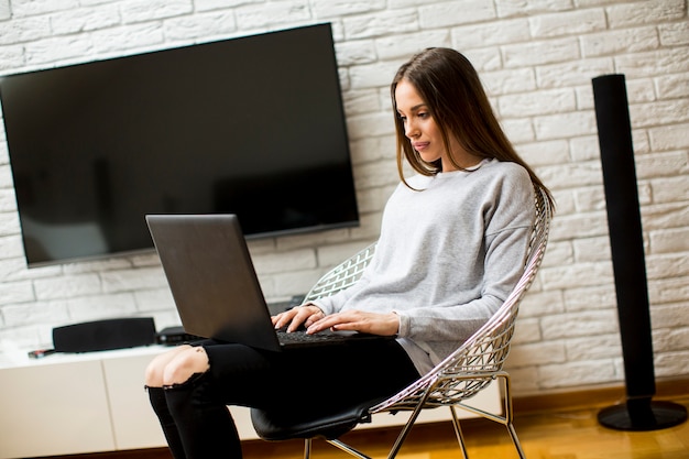 Schöne junge Frau mit Laptop zu Hause