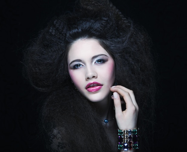 Schöne junge Frau mit lockigem Haar und abendlichem Make-up Schmuck- und Schönheitskonzept Modekunstfoto