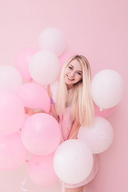 Schöne junge Frau mit Luftballons auf Farbhintergrund