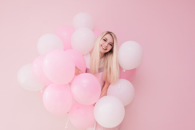 Schöne junge Frau mit Luftballons auf Farbhintergrund