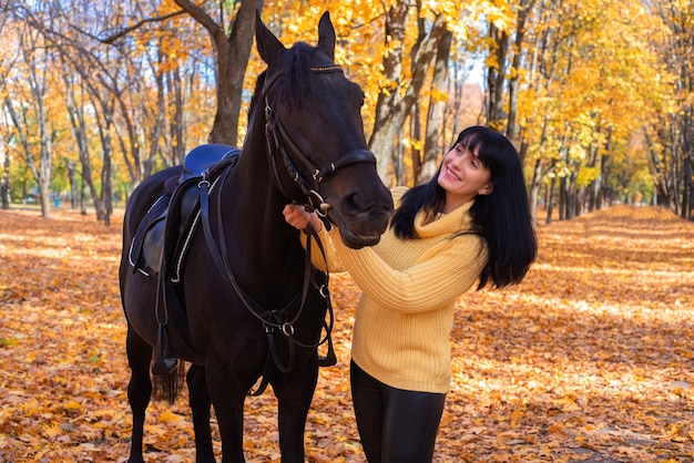 schöne junge Frau mit Pferd im Herbst im Park