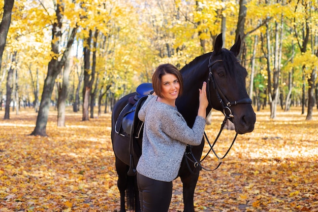 schöne junge Frau mit Pferd im Herbst im Park