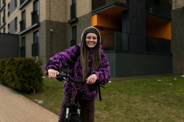 Schöne junge Frau mit Piercing und Dreadlocks fährt Fahrrad in einer städtischen Umgebung