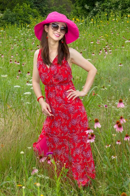 Foto schöne junge frau mit roten blumen auf dem feld