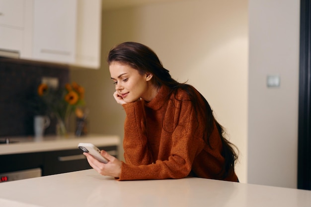 Foto schöne junge frau mit smartphone sitzt an einem modernen home-office-schreibtisch