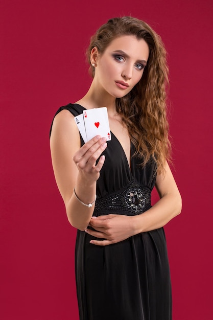 Schöne junge Frau mit Spielkarten auf rotem Hintergrund