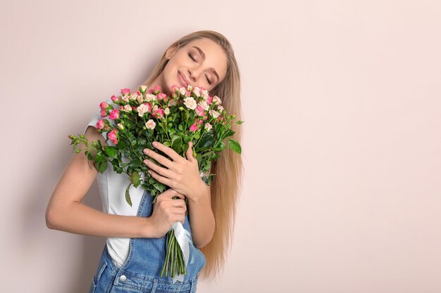 Schöne junge Frau mit Strauß Rosen auf Farbhintergrund