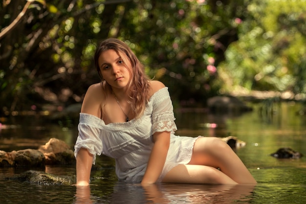 Schöne junge Frau mit weißem Kleid nahe Wasserstrom.