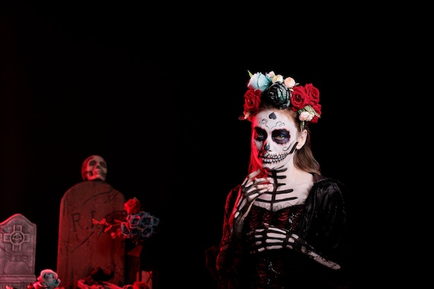 Schöne junge Frau mit Zuckerschädel-Make-up und Rosenkrone, gekleidet in schwarzes Kostüm des Todes als Santa Muerte. Tag der toten Halloween-Kunst zur Feier der heiligen mexikanischen Tradition.