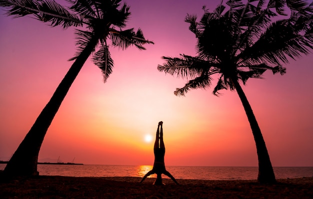 Schöne junge Frau praktizieren Yoga am Strand. Übung am frühen Morgen. Sonnenaufgang