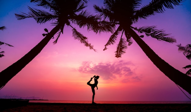 Schöne junge Frau praktizieren Yoga am Strand. Übung am frühen Morgen. Sonnenaufgang