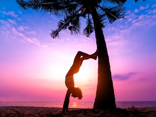 Schöne junge Frau praktiziert Yoga am Strand. Übung am frühen Morgen. Sonnenaufgang