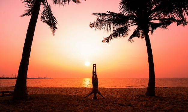 Schöne junge Frau praktiziert Yoga am Strand. Übung am frühen Morgen. Sonnenaufgang
