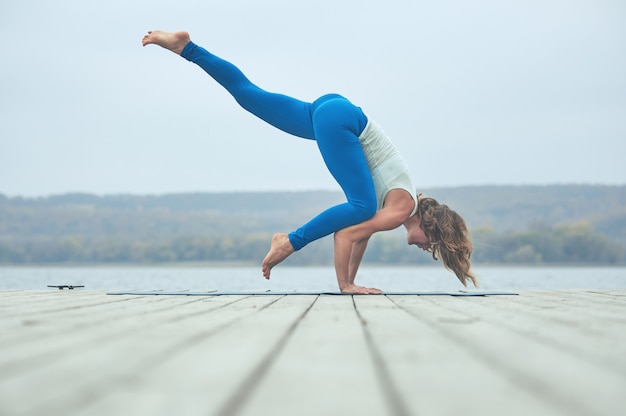 Schöne junge Frau praktiziert Yoga Asana Eka Pada Bakasana