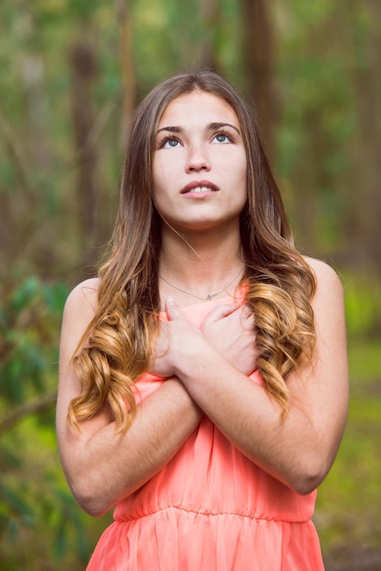 Foto schöne junge frau schaut auf, während sie im wald steht