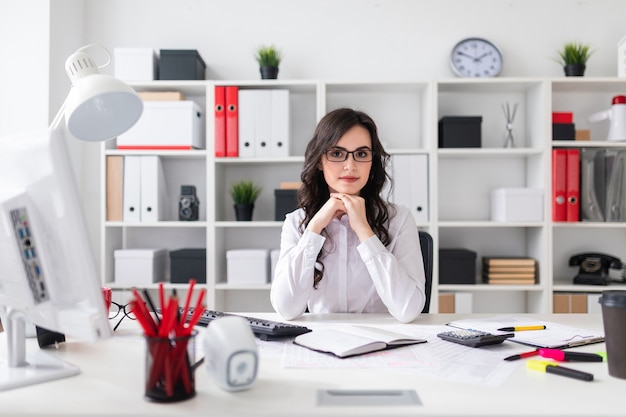 Schöne junge Frau sitzt am Tisch im Büro.