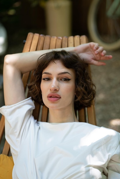 schöne junge Frau sitzt im Sommer draußen in einem hölzernen Stuhl