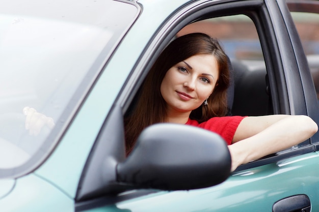 Schöne junge Frau sitzt in einem Autosalon hinter dem Lenkrad. Fahrtraining. Frau fährt