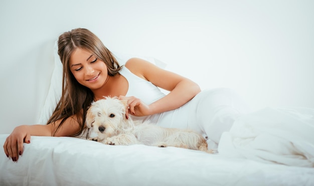 Schöne junge Frau und ihr Hund, die sich morgens im Bett ausruhen.