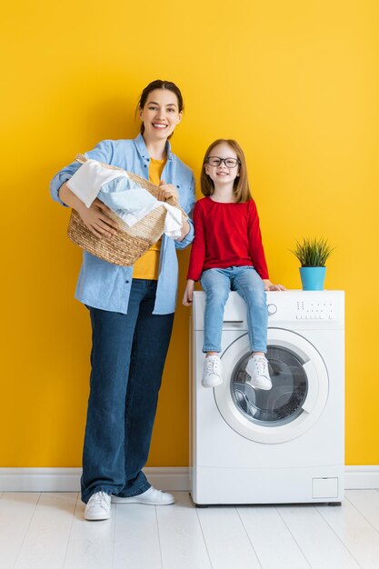 Schöne junge Frau und kleiner Helfer des Kindermädchens haben Spaß und lächeln beim Wäschewaschen zu Hause.