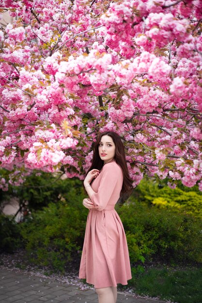 Schöne junge Frau unter dem blühenden rosa Baum.