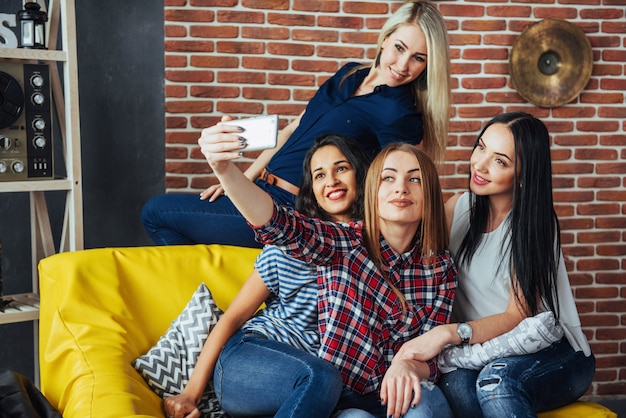 Schöne junge Frau vier, die selfie in einem Café, Mädchen der besten Freunde zusammen haben Spaß, emotionale Lebensstilleute aufwerfend tut