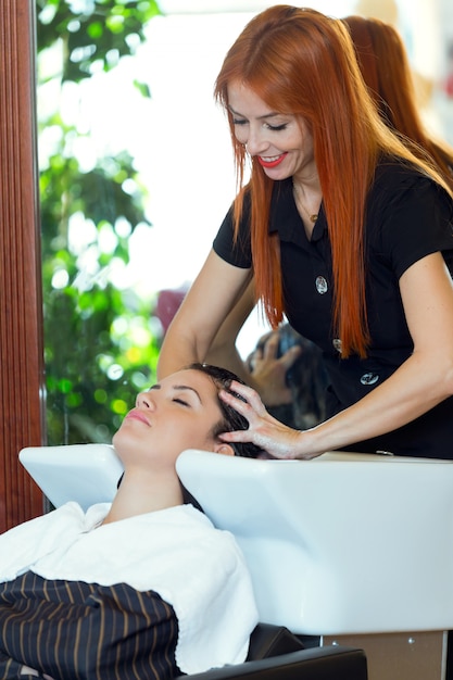 Schöne junge Frau wäscht Haar in einem Schönheitssalon.