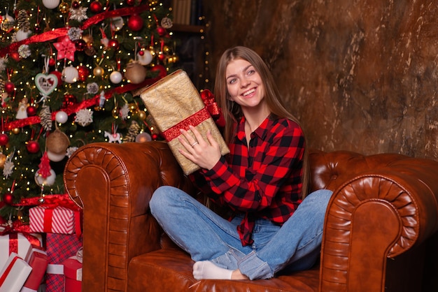 schöne junge frau zu hause zu weihnachten mit geschenken in der nähe des weihnachtsbaums
