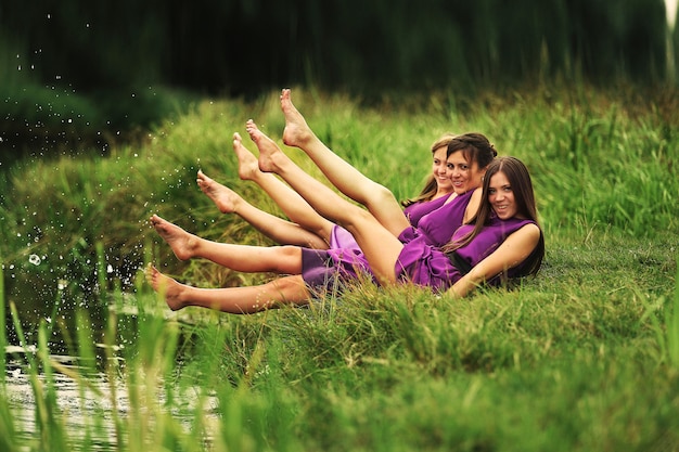 Schöne junge Frauen, Brautjungfern in rosa Kleidern haben Spaß am See an warmen Sommertagen. Hochzeitstag