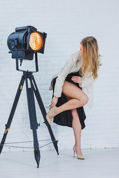 Foto schöne junge frauenbeine in beigen hochhackigen schuhen ein schwarzes langes kleid und eine beige jacke offenes herbst- und frühlingsoutfit mit stöckelschuhen