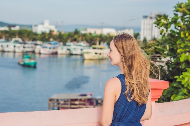 Schöne junge fröhliche Frau vor dem Hintergrund des Meeres und der vietnamesischen Boote.