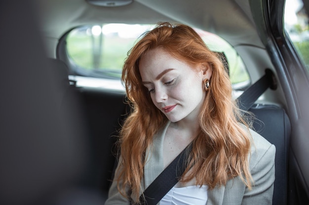 Schöne junge Geschäftsfrau, die auf dem Rücksitz eines Autos sitzt