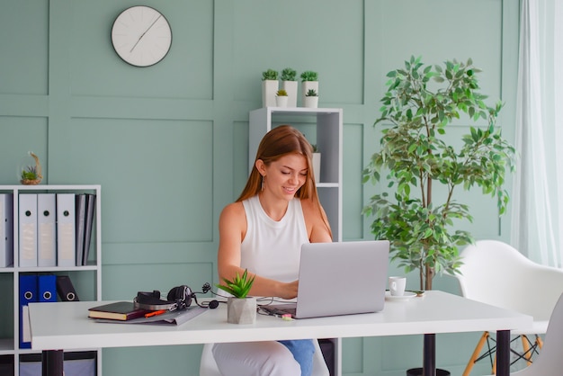 schöne junge Geschäftsfrau, die im Büro am Laptop arbeitet