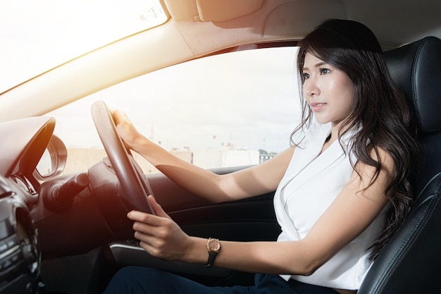 Foto schöne junge glücklich lächelnde frau, die bei sonnenuntergang im auto fährt