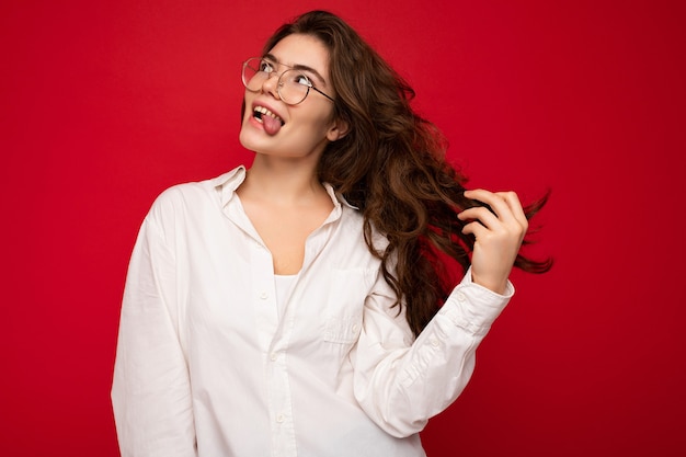 Schöne junge glückliche fröhliche lustige gelockte Brunettefrau, die weißes Hemd und optische Brille trägt