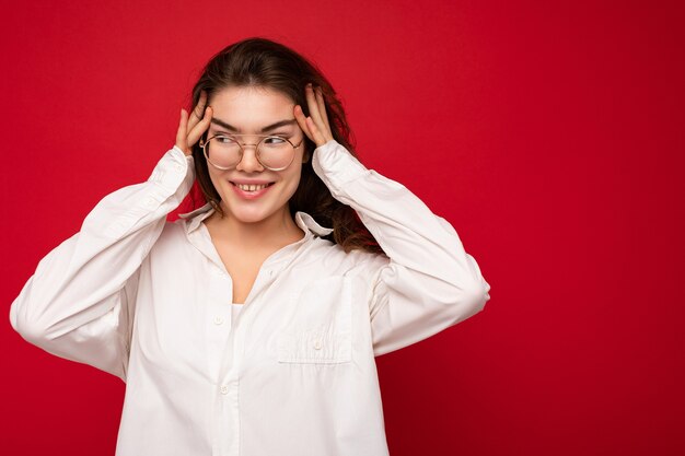 Schöne junge glückliche fröhliche lustige lächelnde gelockte Brunettefrau, die weißes Hemd und optisches trägt