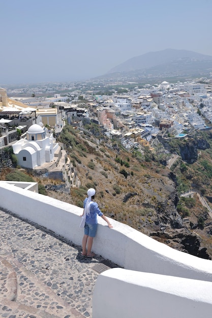 Schöne junge griechische Frau in modischer Kleidung hat Spaß in den Straßen von Oia, Santorini, Griechenland