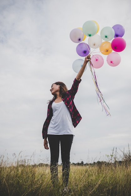 Schöne junge Hipster Frau mit bunten Ballons im Freien, Freiheit genießen mit der Natur. Frauen-Lifestyle-Konzept.