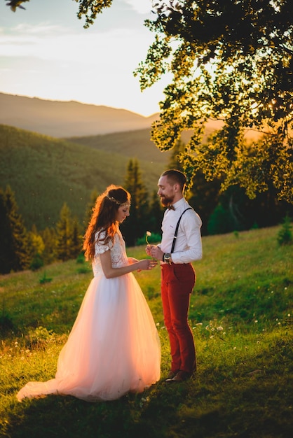 Schöne junge Hochzeitspaare des Bräutigams und der Braut, die auf dem grünen Steigungshügel stehen