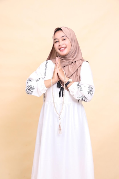 Schöne junge indonesische muslimische Frau im Hijab, die fröhlich Gebetsperlen trägt, während sie mit "ha" gesteht