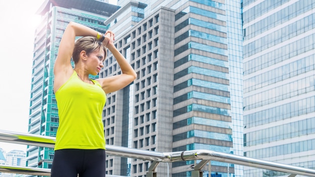 Schöne junge kaukasische Frau in der Fitnesskleidung, die Übungen an der Stadt im Freien tut.