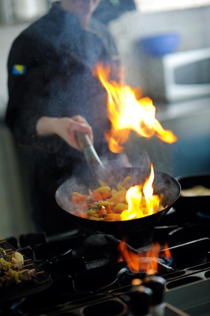 Schöne junge Köchin bereitet leckeres Essen in der Küche zu und dekoriert es