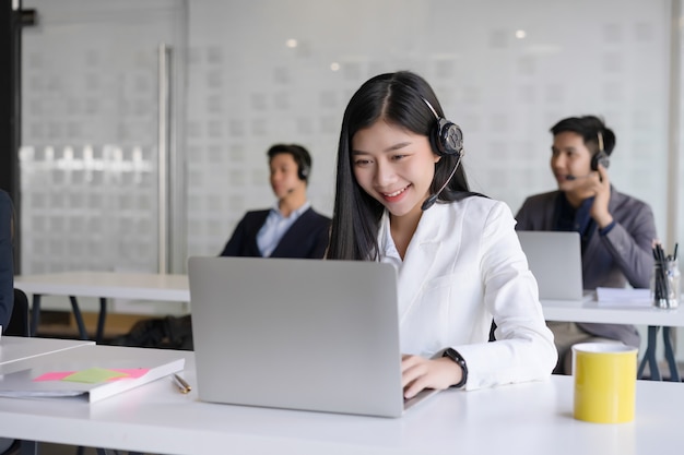 Schöne junge Kundendienstmitarbeiterin mit Headset, das in einem Callcenter-Büro arbeitet.