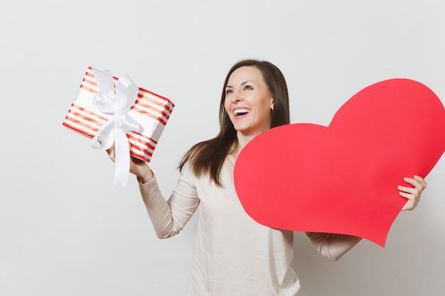 Schöne junge lächelnde Frau, die großes rotes Herz, Kasten mit Geschenk auf weißem Hintergrund hält. Kopieren Sie Platz für Werbung. Mit Platz für Text. Valentinstag- oder Internationaler Frauentag-Konzept.