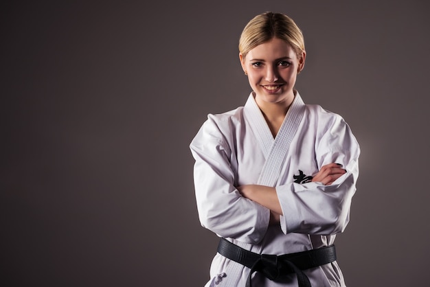 Schöne junge Mädchen blonde Karate-Sportlerin in einem Kimono macht eine Position, um mit dem Training zu beginnen.