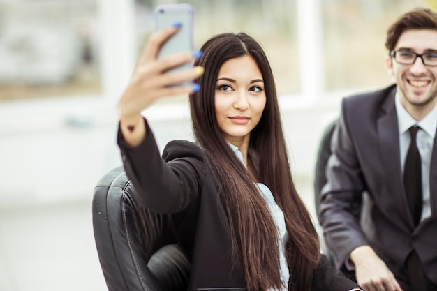 Schöne junge Mitarbeiterin macht mit seinem Kollegen ein Selfie